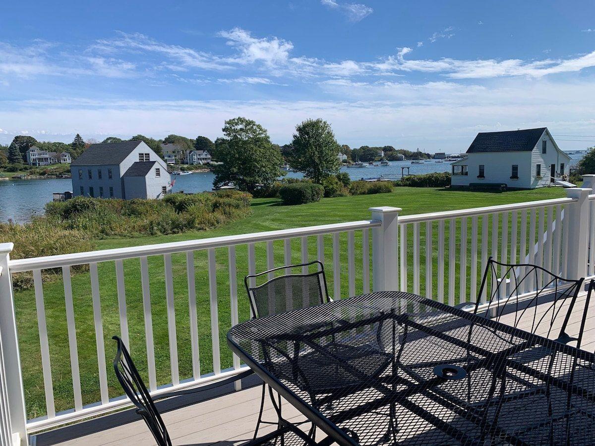 View from the deck table over the lawn to Cape Porpoise harbor, moored boats, and houses on the far shore.