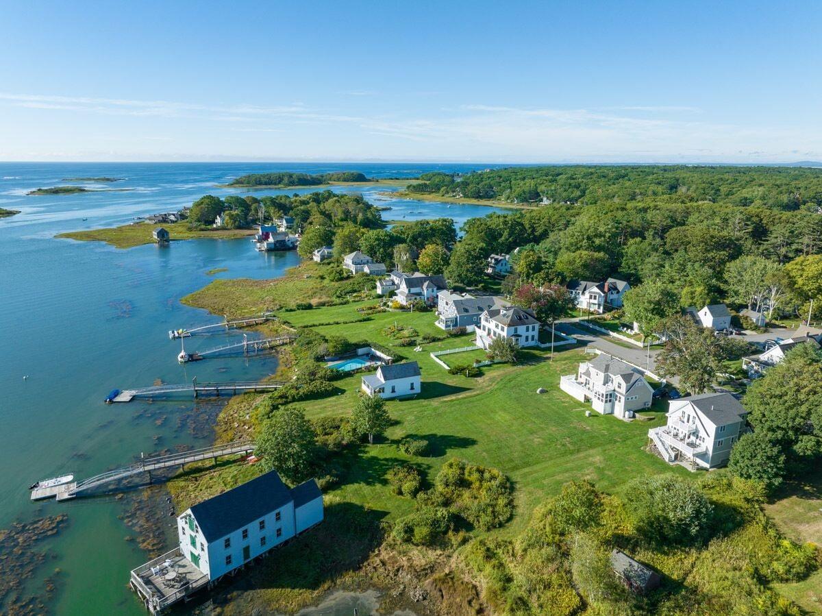 Cape Porpoise harbor from the air: houses along the shore, small docks, moored boats, islands, and open ocean beyond.